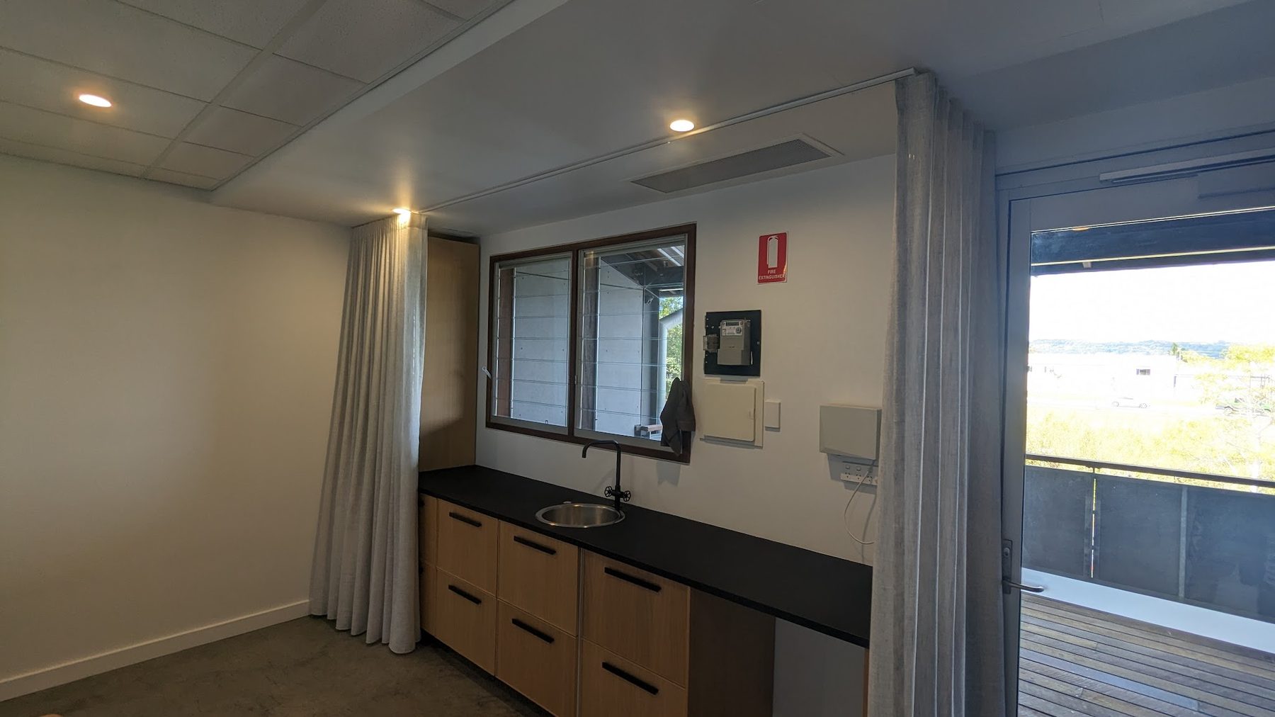 A commercial room with LED downlights, a kitchenette and a switchboard panel on the wall